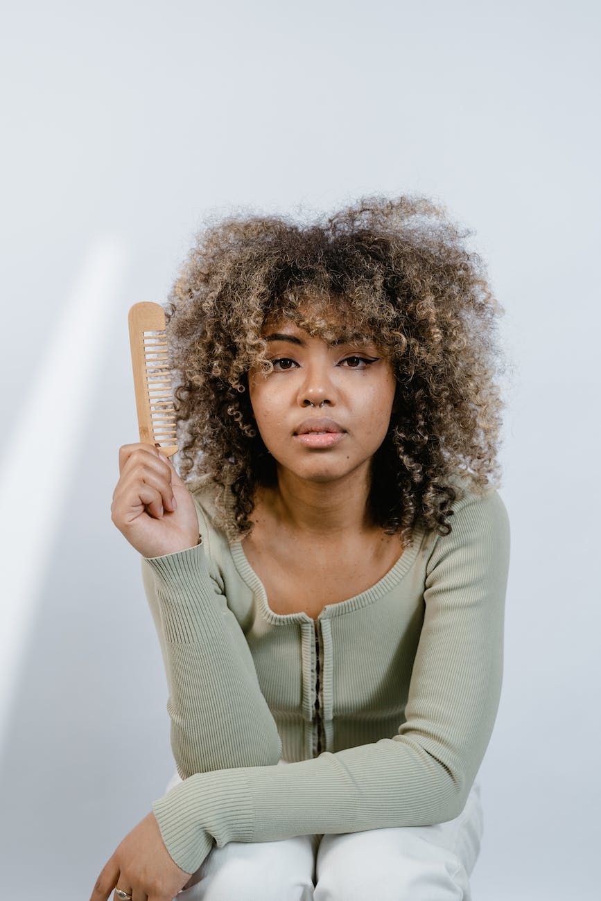 a woman in gray long sleeve shirt holding a wooden comb