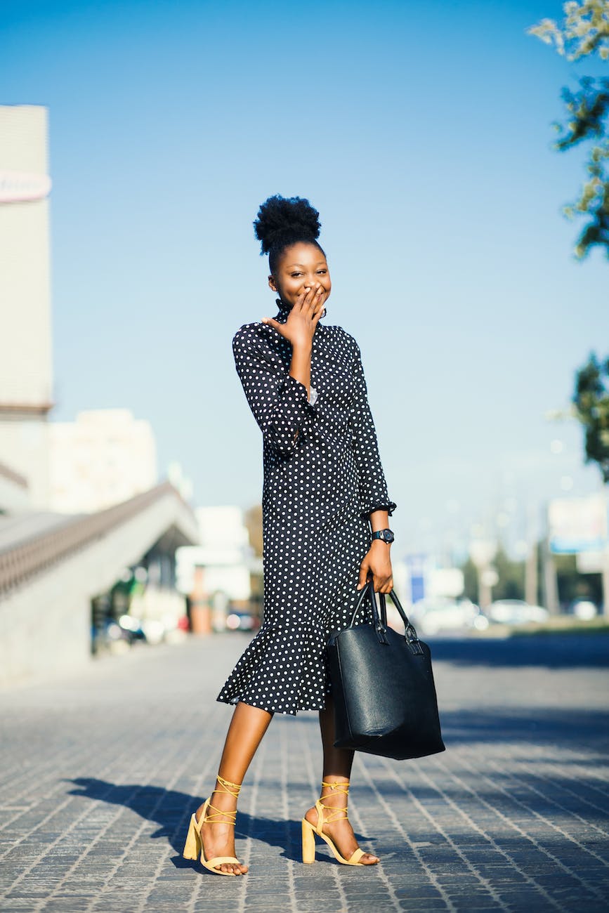 woman standing at outdoors while holding black leather bag - wardrobe essentials